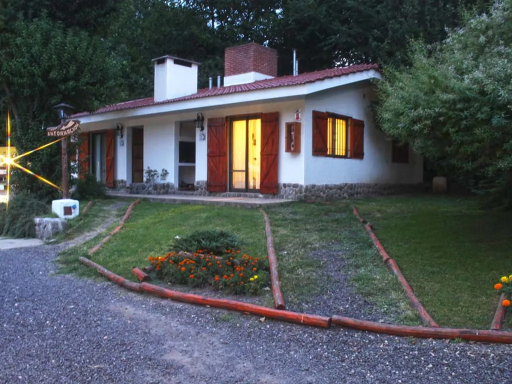 Cabaña blanca con techo de tejas y el jardín, Cabañas Carpe Diem, Villa General Belgrano