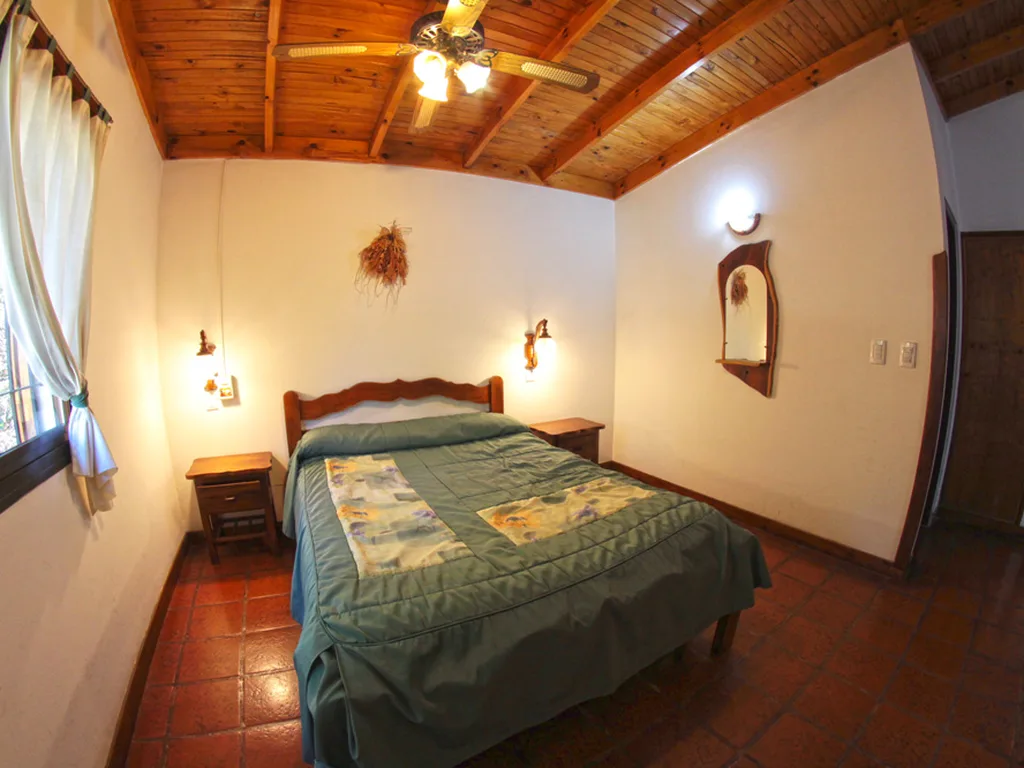 Dormitorio matrimonial con techo de madera, Cabañas Carpe Diem, Villa General Belgrano