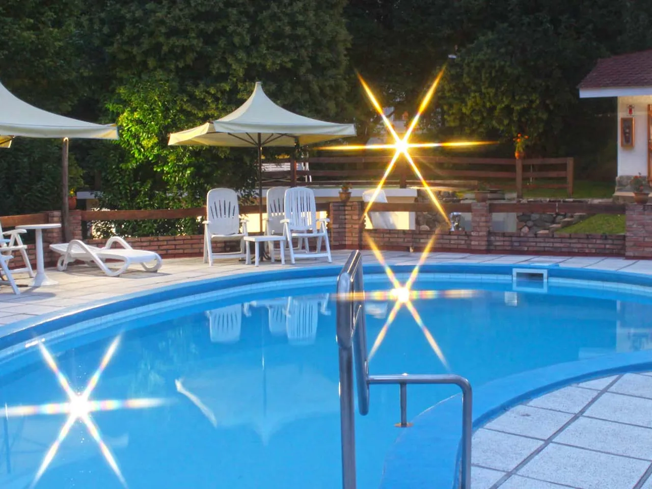 La pileta iluminada de noche, con las cabañas de fondo